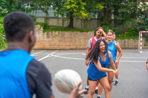 Diverse group of multi ethnic rugby players enjoying training on an outdoor court, passing the ball