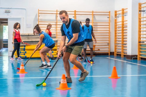 Group of athletes engaging in floorball practice, running with sticks and skillfully hitting the