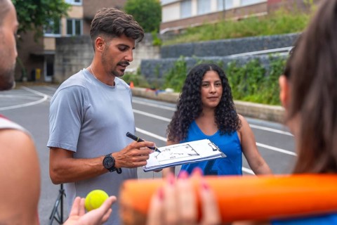 Baseball coach drawing a play on a clipboard while explaining game strategy to his team on an