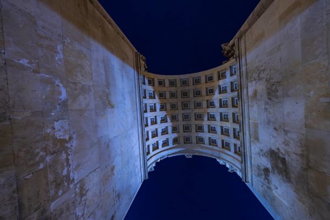 View through a high arcade into the night sky with grid structure, Siegestor, Munich, Germany