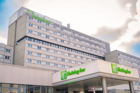 Large Holiday Inn Hotel with several floors in front of a cloudy sky, Munich, Germany