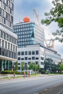 Office complex with neighbouring construction site and crane in the background of a street, Munich,