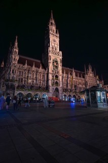 Historic building at night with lighting, people walking around, Munich, Germany