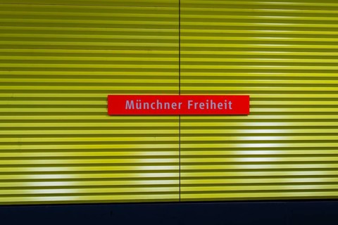 Yellow underground sign with red nameplate 'Münchner Freiheit', Munich, Germany