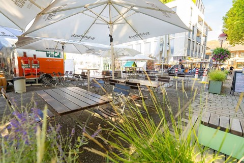 Empty outdoor café with wooden tables, chairs and parasols in a sunny city neighbourhood,