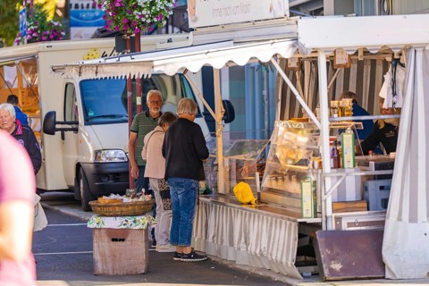 An open-air market stall offers fresh produce, with customers interacting, Sindelfingen, Böblingen