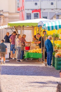 Vendors serving customers at an outdoor market stall with fresh fruit and vegetables, Sindelfingen,