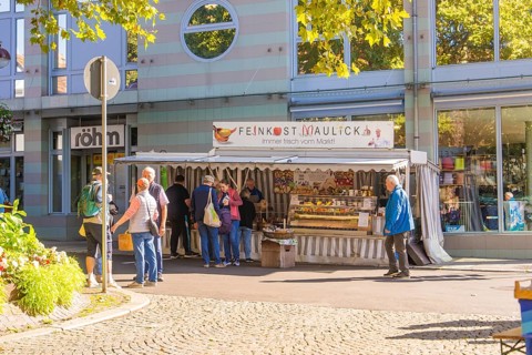 People standing in front of a delicatessen stall surrounded by modern architecture in the city