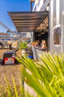 A modern snack stand in a container, surrounded by plants, in sunny weather, Sindelfingen,