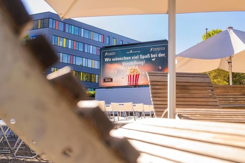 An urban outdoor area with chairs and a screen under parasols, open air cinema Sindelfingen,