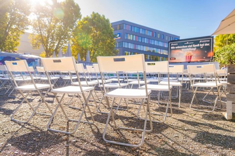 Rows of chairs outdoors under an umbrella in bright sunshine, open air cinema Sindelfingen,