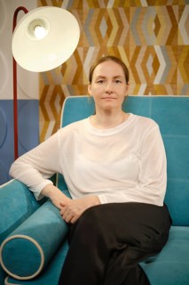 A woman relaxes on a vibrant blue sofa, surrounded by decorative walls featuring geometric patterns