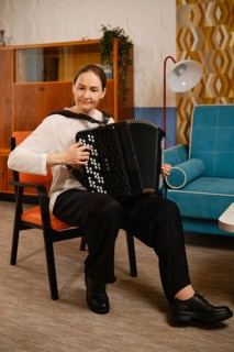 A middle-aged woman is seated comfortably in a vintage living room, skillfully playing the