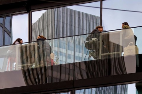 People on the glazed outdoor balcony in a bar with reflection of a skyscraper, Frankfurt am Main,