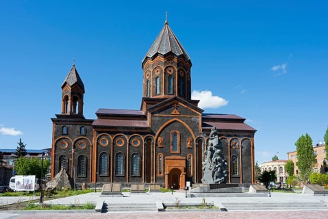 Large church with striking architecture and sculpture in the foreground, clear blue sky, Church of