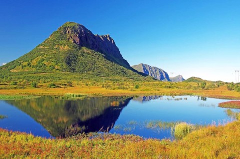 Mountain landscape with lake reflecting the surrounding greenery and clear blue sky, autumn,