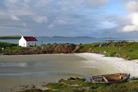 A lonely house and an old boat on a quiet, rocky beach, Isle of Barra, Hebrides, Scotland, United