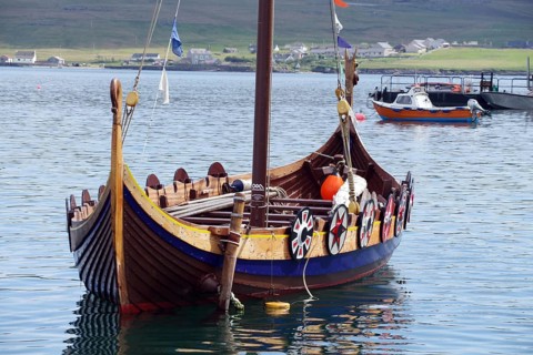 A traditional Viking boat lies decorated in the calm waters of a harbour, Lerwick, Shetland,