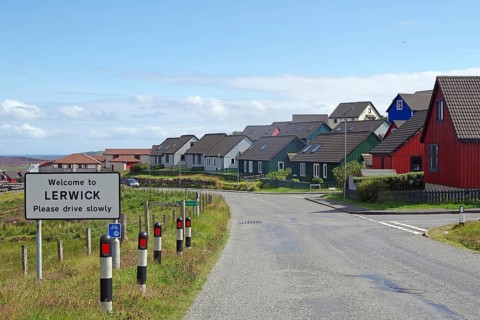 Colourful houses line a street with a welcome sign in a town, Lerwick, Shetland Islands, Scotland,