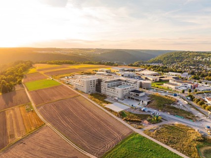 Extensive landscape with a modern building surrounded by fields and hills, new hospital building,