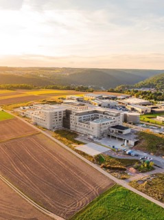Large building in a rural setting with fields and rolling hills at dusk, new hospital building,