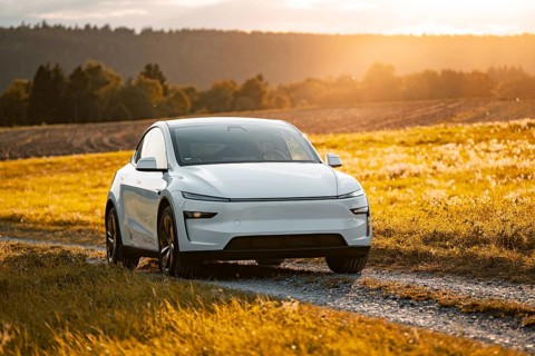 White car on a dirt road in a golden landscape at sunset, Tesla Model Y Juniper, electric car