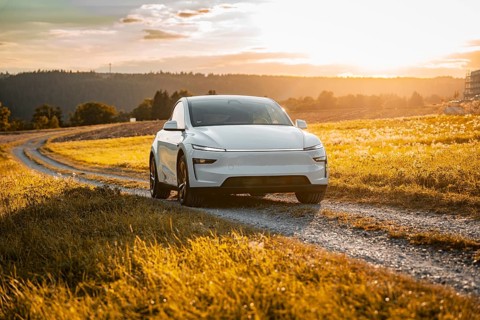 White car on a gravel road through a golden meadow at sunset, Tesla Model Y Juniper, electric car