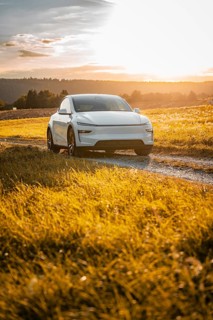 White car on a path surrounded by golden grass at sunset, Tesla Model Y Juniper, electric car