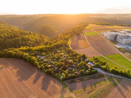 Campsite on the edge of a forest with farmland in the warm light of the setting sun, small town of