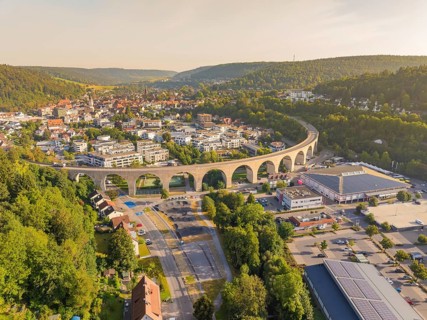 Large viaduct leading over a town and through a hilly landscape, shown from the air, small town of