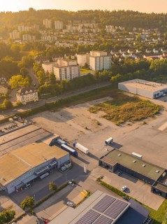 Industrial and residential area at dusk with surrounding nature and urban development, small town