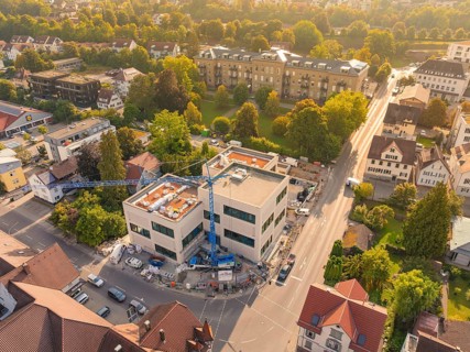 New building in a residential area with crane, surrounded by autumnal colours and streets, small