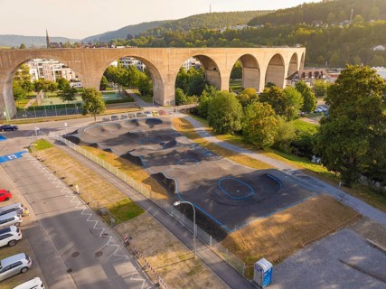 Pump track under a large bridge, surrounded by nature and urban architecture, pump track, Nagold,