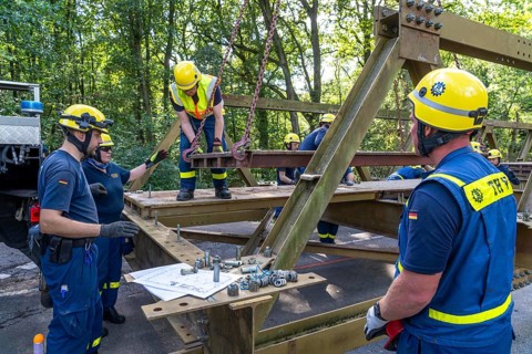 Construction of a temporary bridge over a slipped road crossing a stream, by the bridge