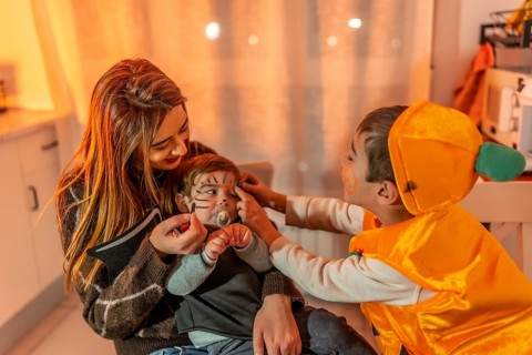 Mother and son applying halloween makeup on baby brother, getting ready for trick or treating