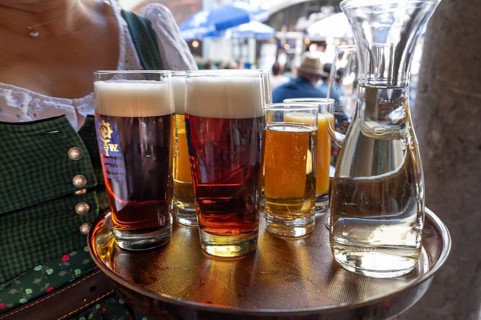 Drinks on a tray are served by a waitress in the beer garden, Munich, Bavaria, Germany