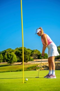 Professional golfer concentrating on the green, about to putt during a sunny day on a beautiful