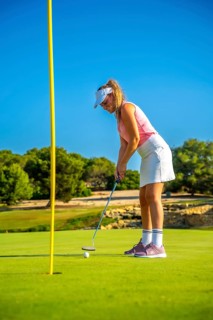 Professional golfer putting a ball on the green under the bright sun, enjoying a beautiful day on a