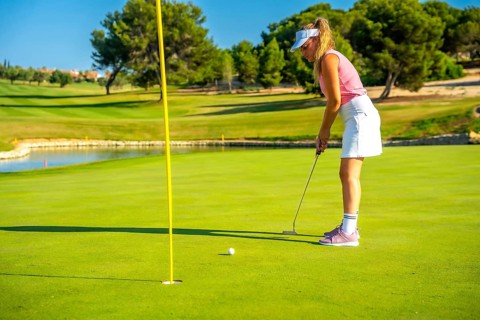 Professional golfer putting the ball on a sunny day, enjoying the beautiful scenery of a lush golf