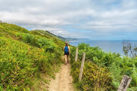 Female tourist enjoying a picturesque hike along the cliffs leading to sakoneta beach in zumaia,