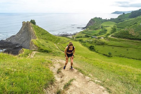 Tired athlete taking a break during trail running workout along the picturesque cliffs of zumaia,