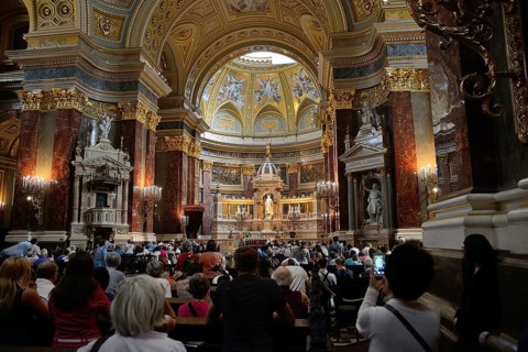Tourists and locals are attending a mass in st. Stephen's basilica, a romanesque catholic basilica