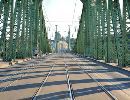 Tourists walking on liberty bridge in budapest, hungary, on a sunny day, with its iconic green