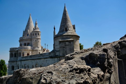Stone wall in the foreground with the fisherman's bastion standing tall against a clear blue sky,