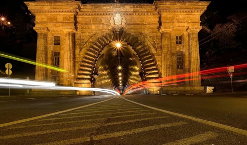 Long exposure photo of cars driving into a tunnel in budapest at night, creating streaks of light