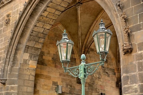 Ornate gas lamp stands beneath a stone arch, showcasing the city's rich history and craftsmanship