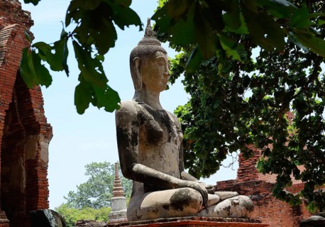 Serene buddha statue sits in peaceful meditation amidst crumbling temple ruins, showcasing