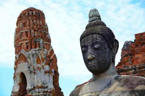 Serene buddha statue stands tall amidst ancient temple ruins, capturing the spiritual essence of