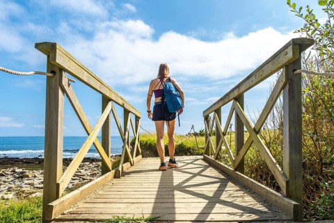 Hiker walking on a wooden walkway leading to sakoneta beach in zumaia, basque country, with flysch