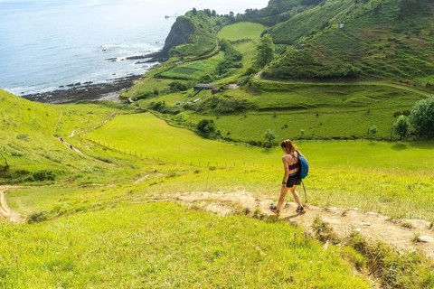 Female hiker walking down a path in the hills near sakoneta beach in zumaia, basque country, spain,